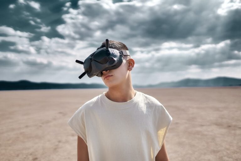 A boy wearing a virtual reality headset in the desert.